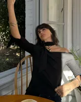 Collar con dije de forma irregular en tonos dorados y plateados, suspendido de un cordón doble de algodón negro.