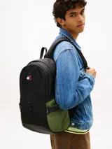 Mochila outdoor Tommy Jeans color negro, con compartimento principal, asa superior, correas ajustables y detalles de malla verde visible en los laterales. Incluye el parche con el logo de la marca bordado en el frente.