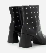Bota de caña corta confeccionada en poliuretano color negro, con punta cuadrada, taco bloque y aplicación de studs metálicos en toda la superficie. Cuenta con cierre lateral.