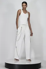 Pantalón blanco de corte amplio y fluido, con tiras colgantes de strass decorativas en los laterales.