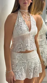 Minifalda blanca con lentejuelas plateadas, de tiro bajo y diseño acampanado.