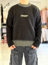 Sweater tejido de punto grueso con efecto gastado o degrade en cuello y ruedo, de corte holgado, mangas largas y cuello redondo. Cuenta con un bordado frontal con el texto "WCP".