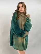 Buzo tejido de lana merino con diseño oversize, manga ranglan y cuello levemente elevado. Presenta un efecto de teñido degradado que combina tonos verdes y beige.