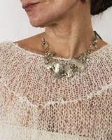 Gargantilla de diseño artesanal compuesta por eslabones metálicos con textura orgánica y acabado irregular. El diseño se ajusta al cuello mediante un cordón regulable.