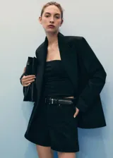 Short de denim negro de tiro alto, con cinco bolsillos, trabillas para cinto y cierre frontal con cremallera y botón.