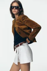 Falda pantalón blanca de tiro alto con cinturón marrón y delantero cruzado. Cierre lateral con cremallera oculta.