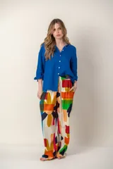 Pantalón de corte holgado con cintura elastizada, confeccionado en tela estampada con motivos geométricos y florales abstractos en colores vibrantes sobre fondo claro.