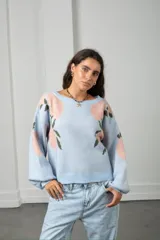 Buzo de punto en color celeste con estampado floral en tonos rosados y verdes. Presenta un diseño de cuello redondo, corte holgado y mangas largas abullonadas con puños ajustados.