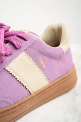 Zapatilla urbana de gamuza color lila con detalles en beige y suela marrón.
