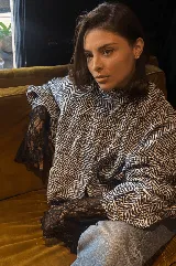 Campera bomber oversize de paño italiano con estampado en zigzag blanco y negro, cuello alto y cierre frontal con broches a presión. Tiene mangas murciélago.