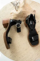 Sandalias de cuero color beige con plataforma y taco cuadrado de madera. Presentan una tira frontal ancha y una tira ajustable en el tobillo con hebilla metálica plateada.