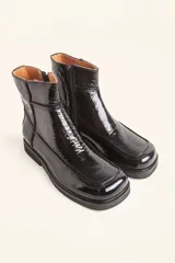 Bota corta de cuero vacuno con acabado charol brillante, diseño de punta cuadrada y suela de caucho con pequeña plataforma.