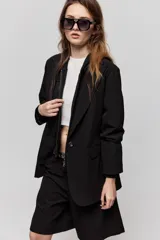Blazer sastrero negro de calce relajado, con solapa clásica, cierre de un botón frontal y bolsillos laterales con tapa.