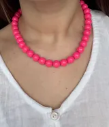 Collar corto de cuentas esféricas de resina color fucsia.
