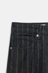 Jeans de tiro bajo y corte recto, confeccionados en denim negro con estampado de rayas verticales finas. Presentan cinco bolsillos, trabillas para cinturón y cierre frontal con cremallera y botón metálico.