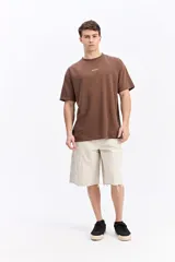 Remera de manga corta color beige con tejido texturado y pequeño logo impreso en el pecho.