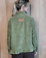 Sobrecamisa de pana color marrón oscuro, con cuello camisero, cierre frontal de botones y detalle de volado en el ruedo. Presenta mangas largas con puños y bolsillos frontales aplicados.