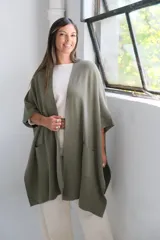 Poncho abierto de tejido de punto color verde oliva, con mangas cortas tipo kimono y bolsillos frontales aplicados.