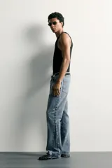 Jeans flare fit de hombre confeccionados en denim de algodón color azul con efecto lavado y roturas. Presentan diseño de cinco bolsillos, efecto salpicaduras de pintura en toda la prenda y bajo con acabado irregular.