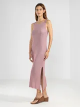 Vestido midi sin mangas, tejido en punto jersey con hilo Lurex que aporta un brillo sutil. Presenta escote bote redondeado y aberturas laterales en el ruedo.