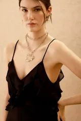 Vestido corto negro de viscosa georgette, con escote en V, volados en el frente y espalda descubierta. Cuenta con breteles finos ajustables que se atan en la espalda y ajuste elástico en la cintura.