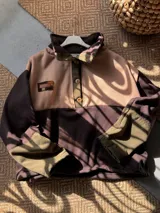 Buzo oversize de friza de algodón y poliéster, con diseño colorblock en tonos verde militar, marrón y rosado. Cuenta con cuello alto, solapa con botones frontales y mangas largas.