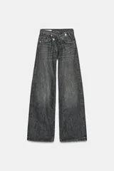 Jeans de tiro alto con diseño de pierna ancha y corte extra largo. Presenta una cintura cruzada asimétrica con cierre de cremallera y botones metálicos, además de un diseño clásico de cinco bolsillos.
