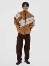 Campera de denim estilo deportivo con diseño de paneles en tonos azul claro y blanco, cuello alto, cierre frontal y bolsillos laterales con cierre. Presenta corte oversized con puños y cintura elásticos.