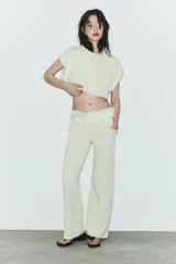 Pantalón verde claro de tiro medio, con bolsillos delanteros y cintura ajustable con cordones y volantes del mismo tejido.