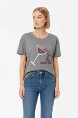 Remera de algodón color gris, de manga corta y cuello redondo. Presenta un estampado frontal de una copa de cóctel de la que emergen labios rojos con lentejuelas.