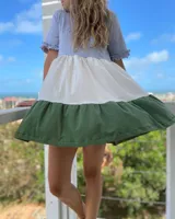 Vestido corto de corte evasé con paneles de color gris en la parte superior, blanco en el centro y verde en el ruedo. Tiene mangas cortas con volados.