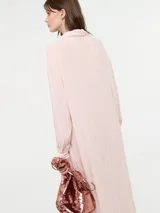 Camisa larga de corte oversize, color rosado, con cuello camisero, cierre frontal con botones y mangas largas.
