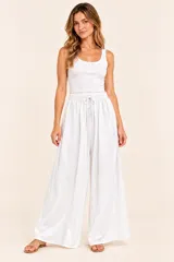 Pantalón blanco de tiro alto, corte holgado y pierna ancha tipo palazzo, con cintura elástica fruncida y cordón ajustable.
