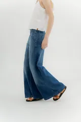 Pantalón de jean de tiro medio y pierna ancha, confeccionado en denim 100% algodón. Diseño con 5 bolsillos y pespuntes a contratono.