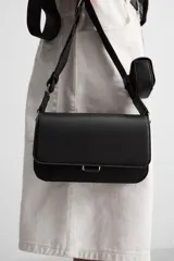 Bandolera negra con acabado grabado, compartimento principal con cierre de solapa imantada, bolsillo interno con cierre y bolsillo frontal con cierre. Incluye asa de hombro ajustable y monedero.