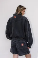 Campera de denim color negro con efecto lavado, corte semi oversize, cierre frontal completo, cuello camisero y bolsillos laterales.