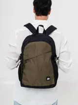 Mochila urbana de diseño bicolor en negro y verde oliva. Cuenta con un compartimento principal amplio, bolsillo frontal diagonal con cierre, bolsillos laterales de red y correas laterales de compresión. Incluye correas acolchadas ajustables para mayor comodidad.