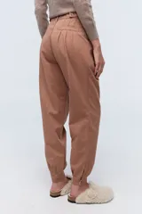 Pantalón estilo babucha color marrón, con pinzas en la cintura y puños elásticos en los tobillos.