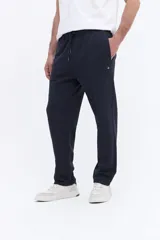 Pantalón de jogging con corte recto y ajuste relajado, confeccionado en tejido de algodón y poliéster. Cuenta con cintura elástica con cordón de ajuste y bolsillos laterales funcionales.