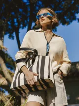 Bolso amplio con doble manija y correa al hombro, con diseño a rayas verticales blancas y negras.