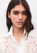 Camisa blanca de manga larga con detalles bordados calados en el frente y puños anchos.