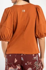 Remera de algodón negro con mangas cortas abullonadas, cuello redondo y costura central frontal.