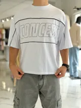 Remera blanca de corte boxy fit, con diseño de líneas negras horizontales y la palabra "CONCEPT" estampada en el frente con contorno negro.