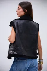 Chaleco de cuero sintético con acabado gamuzado, forrado en corderito negro. Presenta cierre frontal, cuello solapa, detalles de correas ajustables en los laterales y ribetes de corderito en los bordes.