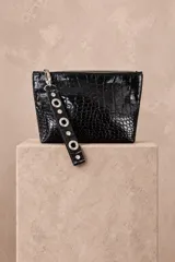 Sobre de mano negro con textura símil cocodrilo y acabado brillante, cierre superior y tira de muñeca con argollas metálicas.