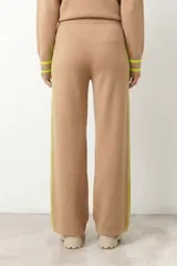 Pantalón de punto rib color beige, de corte recto y holgado, con una línea vertical lateral en color amarillo neón.