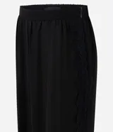 Pantalón balloon de crepé negro, de corte amplio y cintura elástica, con detalles de encaje en los laterales y puños inferiores elastizados.