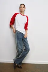 Camiseta de manga larga con diseño ranglan, cuerpo en color blanco y mangas en color rojo. Presenta cuello redondo y bajo recto.