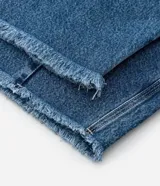 Pantalón de jean azul de corte barrel, con pences delanteros, cintura con trabillas, cierre tradicional y terminación deshilachada.