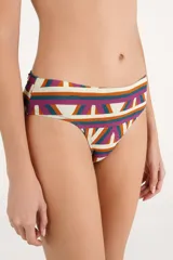 Bombacha de bikini tiro alto con faja ancha drapeada y diseño estampado geométrico multicolor en tonos beige, fucsia, naranja y verde.